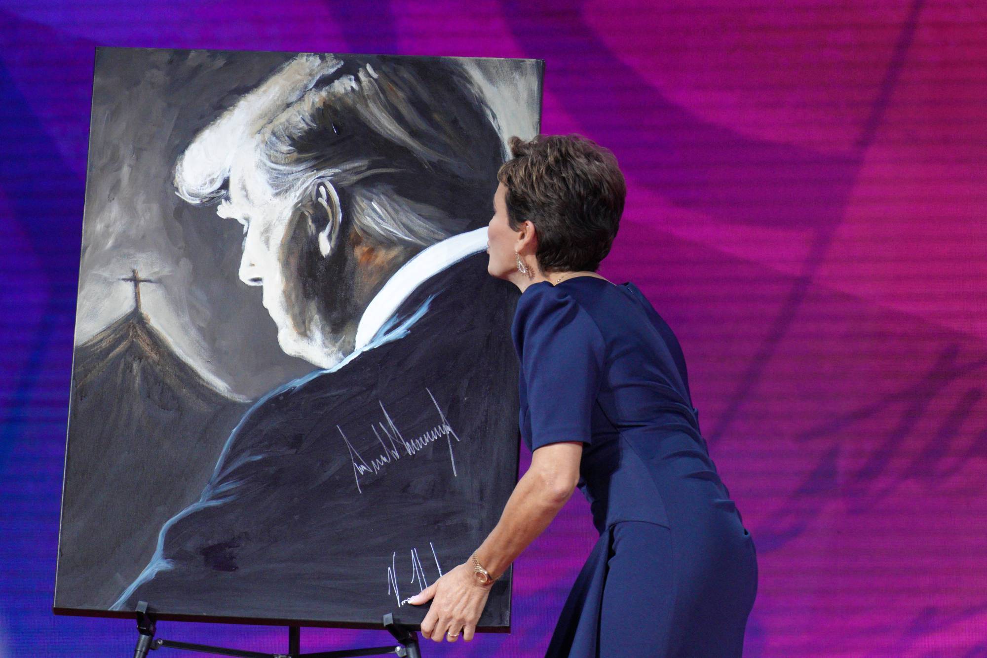 Kari Lake, former candidate for Governor of Arizona, kisses a portrait of Trump after speaking at the CPAC gathering on Friday. | Reuters