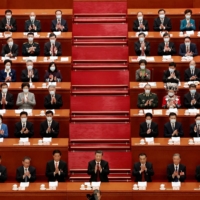 Chinese leader Xi Jinping and other officials applaud at the opening session of the National People\'s Congress in Beijing on Sunday. | REUTERS