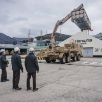 Hanhwa Aerospace engineers look on as a support vehicle unloads a multiple-rocket container during a test run at the factory. | JUN MICHAEL PARK / THE NEW YORK TIMES