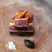 Chef Haruki Sato grills wild duck breast together with charcoal-grilled carrots that have been harvested from under the deep snow. | KOUTAROU WASHIZAKI
