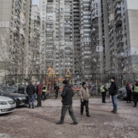 Residents and police officers at the scene where missile parts fell onto a residential parking lot and destroyed several cars in the Sviatoshynskyi district of Kyiv on Thursday | LAETITIA VANCON / THE NEW YORK TIMES