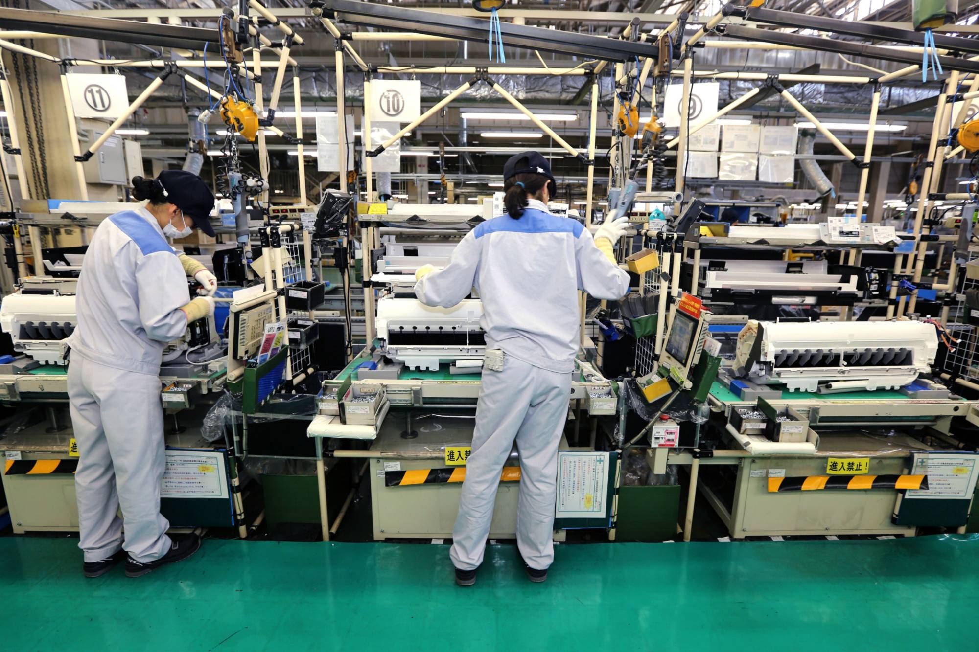 Workers assemble indoor units of Daikin Industries split type air conditioners at the company's plant in Kusatsu, Shiga Prefecture, in August 2017. The firm has plans to establish an air-conditioner production supply chain without relying on Chinese components. | BLOOMBERG