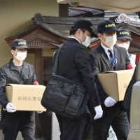 Police investigators carry cardboard boxes from Daimaru Besso in Chikushino, Fukuoka Prefecture, on Friday after searching the inn. | KYODO