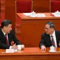 Chinese President Xi Jinping (left) speaks with Politburo Standing Committee member Li Qiang during the third plenary session of the National People\'s Congress in Beijing on Friday | AFP-JIJI