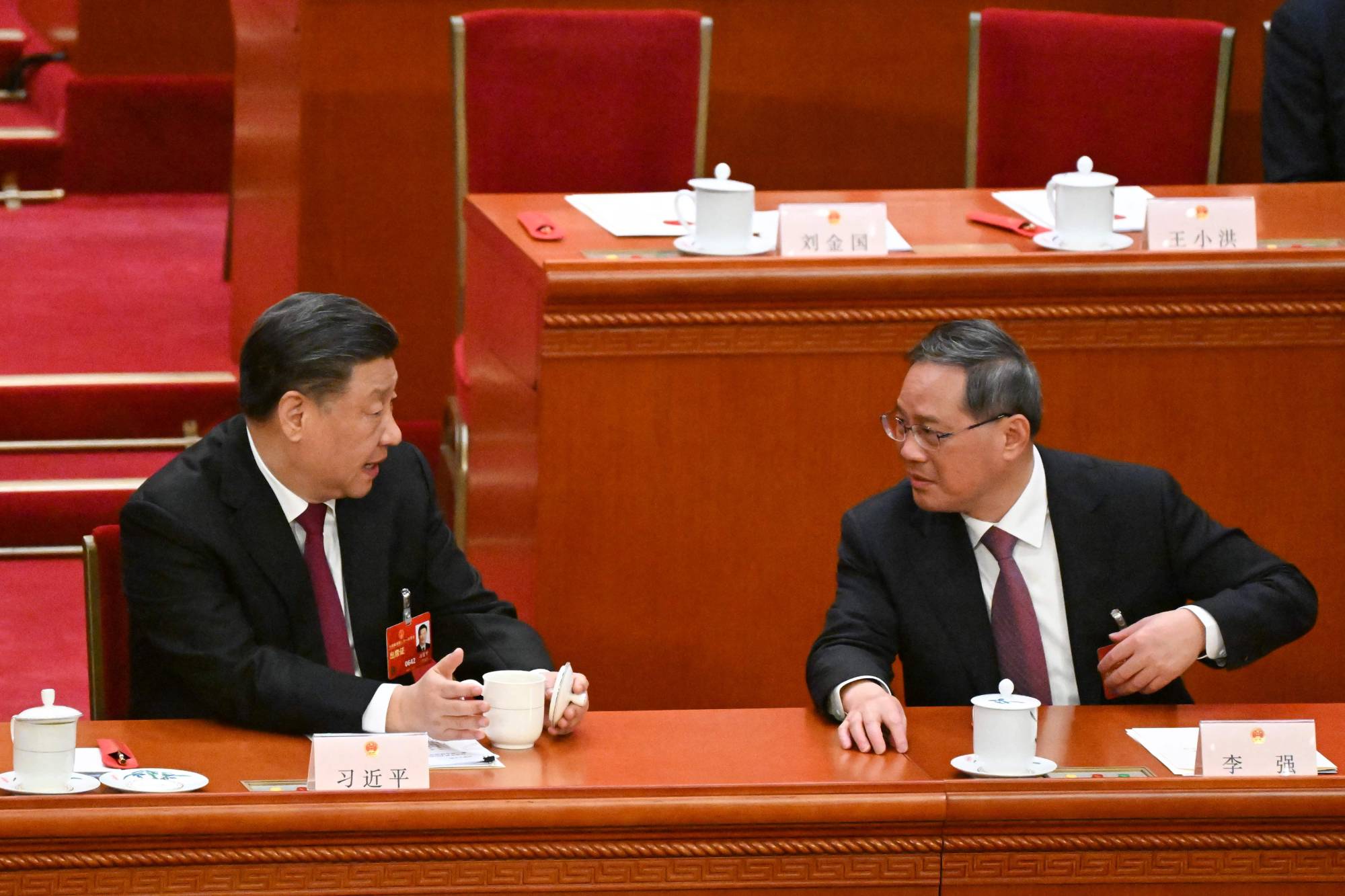 Chinese President Xi Jinping (left) speaks with Politburo Standing Committee member Li Qiang during the third plenary session of the National People's Congress in Beijing on Friday | AFP-Jiji