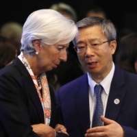 Yi Gang, governor of the People\'s Bank of China, speaks with Christine Lagarde, managing director of the International Monetary Fund, during a Group of 20  meeting in Fukuoka in June 2019.   | POOL / VIA BLOOMBERG