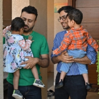 A same-sex couple take their adopted children for a walk outside their home in Bengaluru, India, in February.   | AFP-JIJI