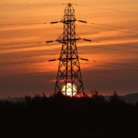 The sun rises behind an electricity transmission tower in the U.K. | BLOOMBERG