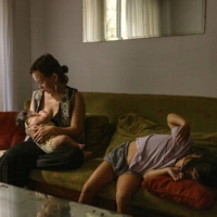 Irina Bugaeva nurses her 4-month-old son Duolan, who was born in Buenos Aires, while her daughter Leia plays on the sofa at their apartment in the capital of Argentina. | SARAH PABST / THE NEW YORK TIMES