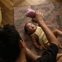 Aisen Sergeev plays with he and his wife\'s 4-month-old son Duolan, who was born in Buenos Aires, at their apartment in the capital of Argentina | SARAH PABST / THE NEW YORK TIMES