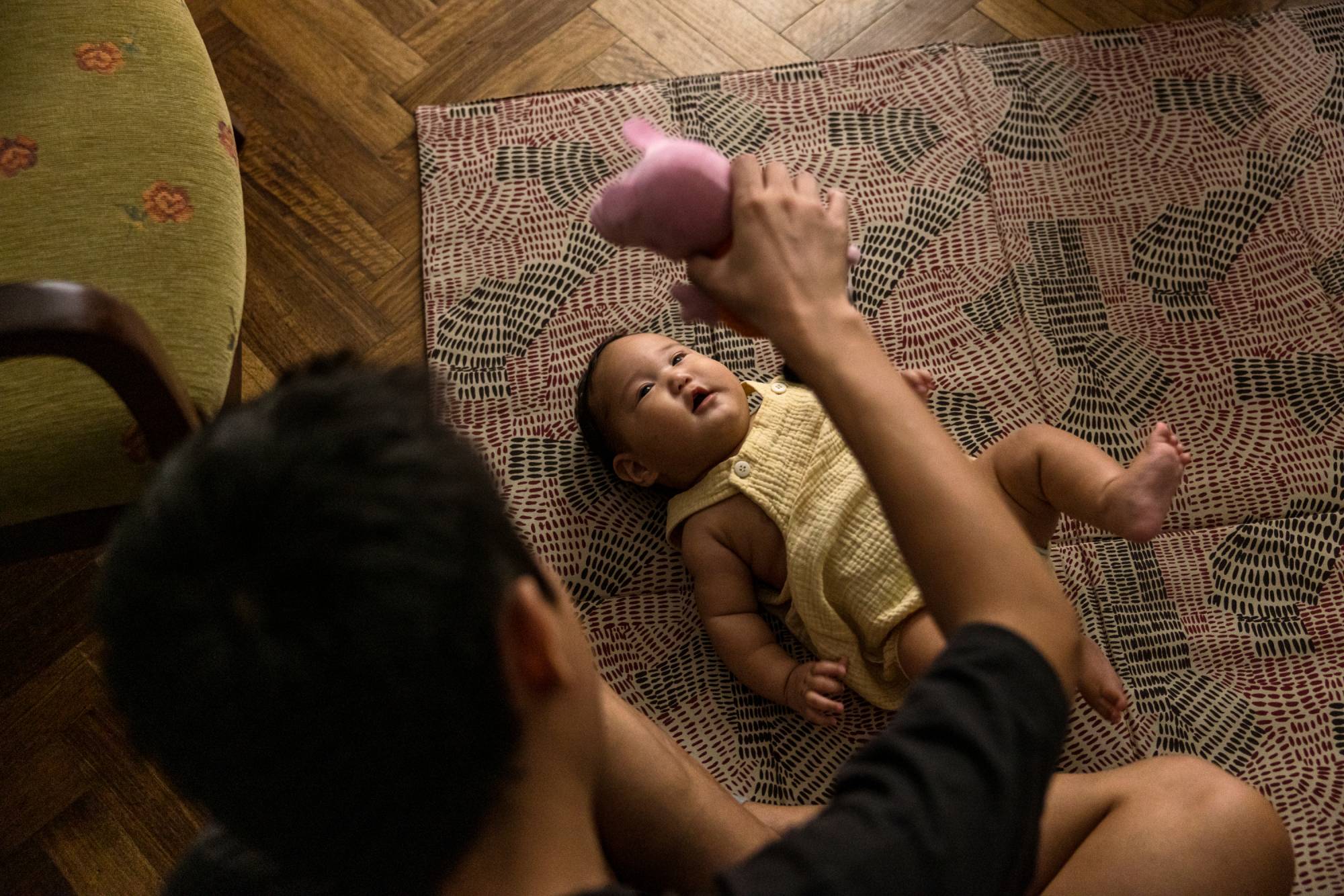 Aisen Sergeev plays with he and his wife's 4-month-old son Duolan, who was born in Buenos Aires, at their apartment in the capital of Argentina | Sarah Pabst / The New York Times