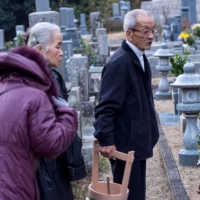 Japanese people visit the graves of their families with a special ladle and pail that will be used for cleaning the tombstones. | GETTY IMAGES