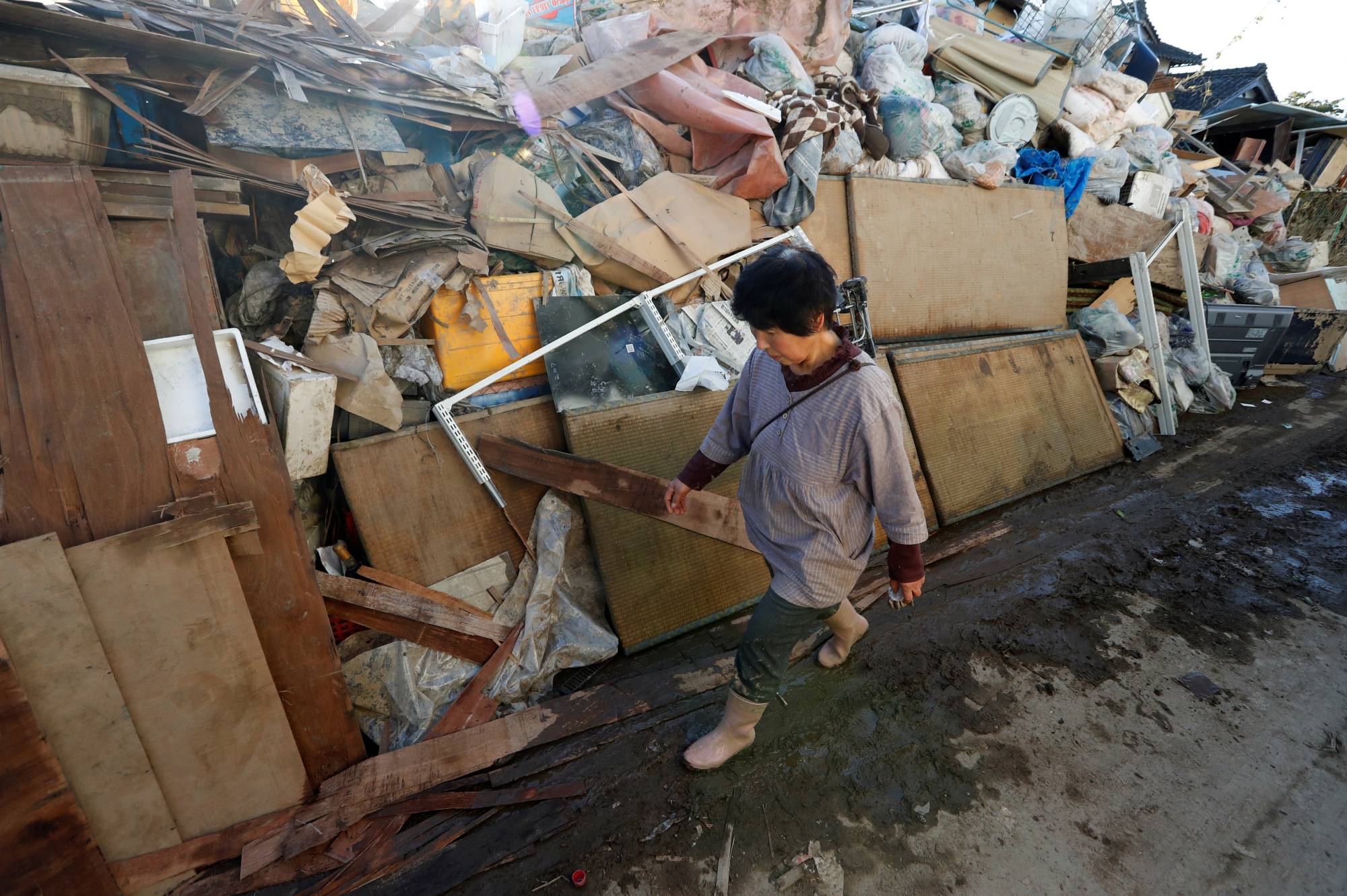 A woman walks past debris in the aftermath of Typhoon Hagibis in the city of Date, Fukushima Prefecture, in October 2019. Japan expects more severe typhoons and as much as 1.5 times more rainfall by the end of the century, both of which will increase the risk of flooding. | REUTERS