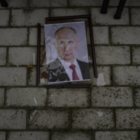 A smashed portrait of Russian President Vladimir Putin hangs outside a police prison used to hold and torture Ukrainian prisoners by Russian forces in Kherson, Ukraine, in November. | LYNSEY ADDARIO / THE NEW YORK TIMES
