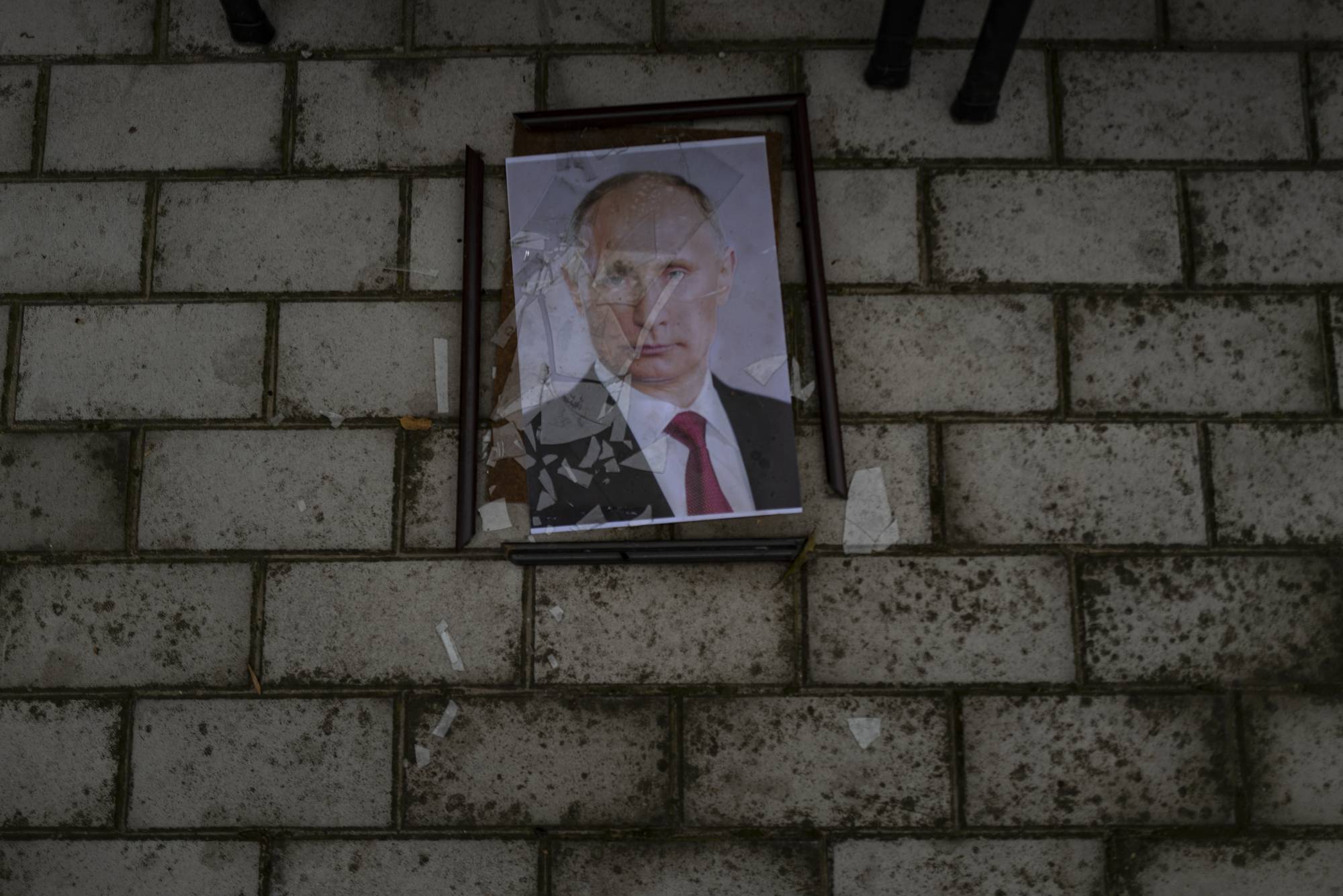 A smashed portrait of Russian President Vladimir Putin hangs outside a police prison used to hold and torture Ukrainian prisoners by Russian forces in Kherson, Ukraine, in November. | LYNSEY ADDARIO / THE NEW YORK TIMES