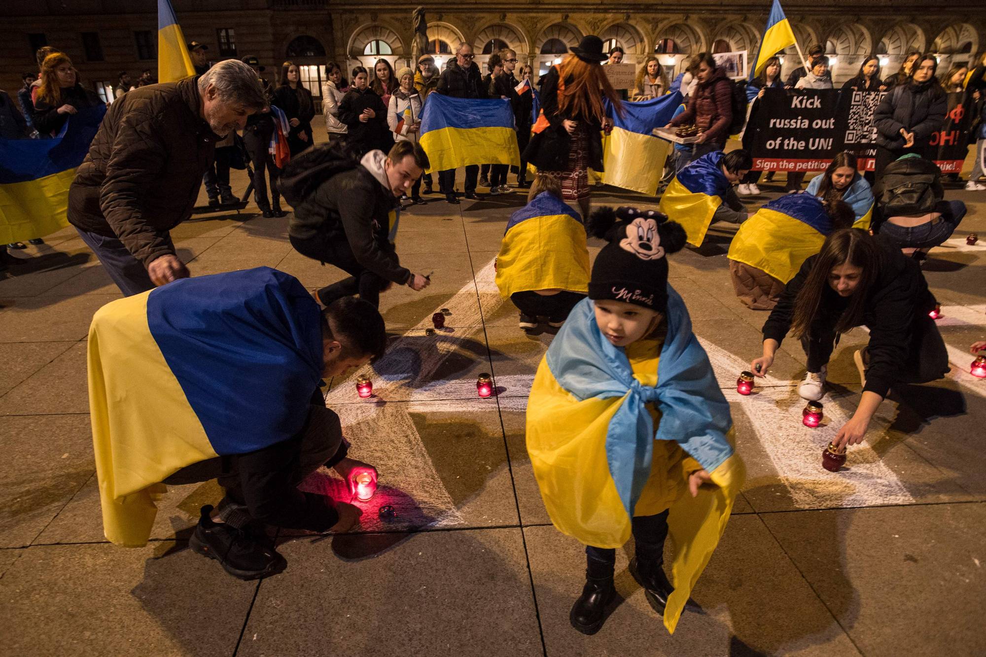 Ukrainians living in the Czech Republic draw lettering in Russian on Saturday reading 'children' during a rally commemorating people killed a year ago inside the Mariupol Drama Theater building in Ukraine by a Russian air strike. | AFP-JIJI