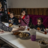 Children evacuated from Kramatorsk because of heavy shelling near their home eat a meal provided by a nongovernmental organization in Pokrovsk, Ukraine, on March 1.  | DANIEL BEREHULAK / THE NEW YORK TIMES