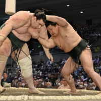Midorifuji (right) attacks Aoiyama during their Day 8 bout at Edion Arena Osaka on Sunday. | KYODO