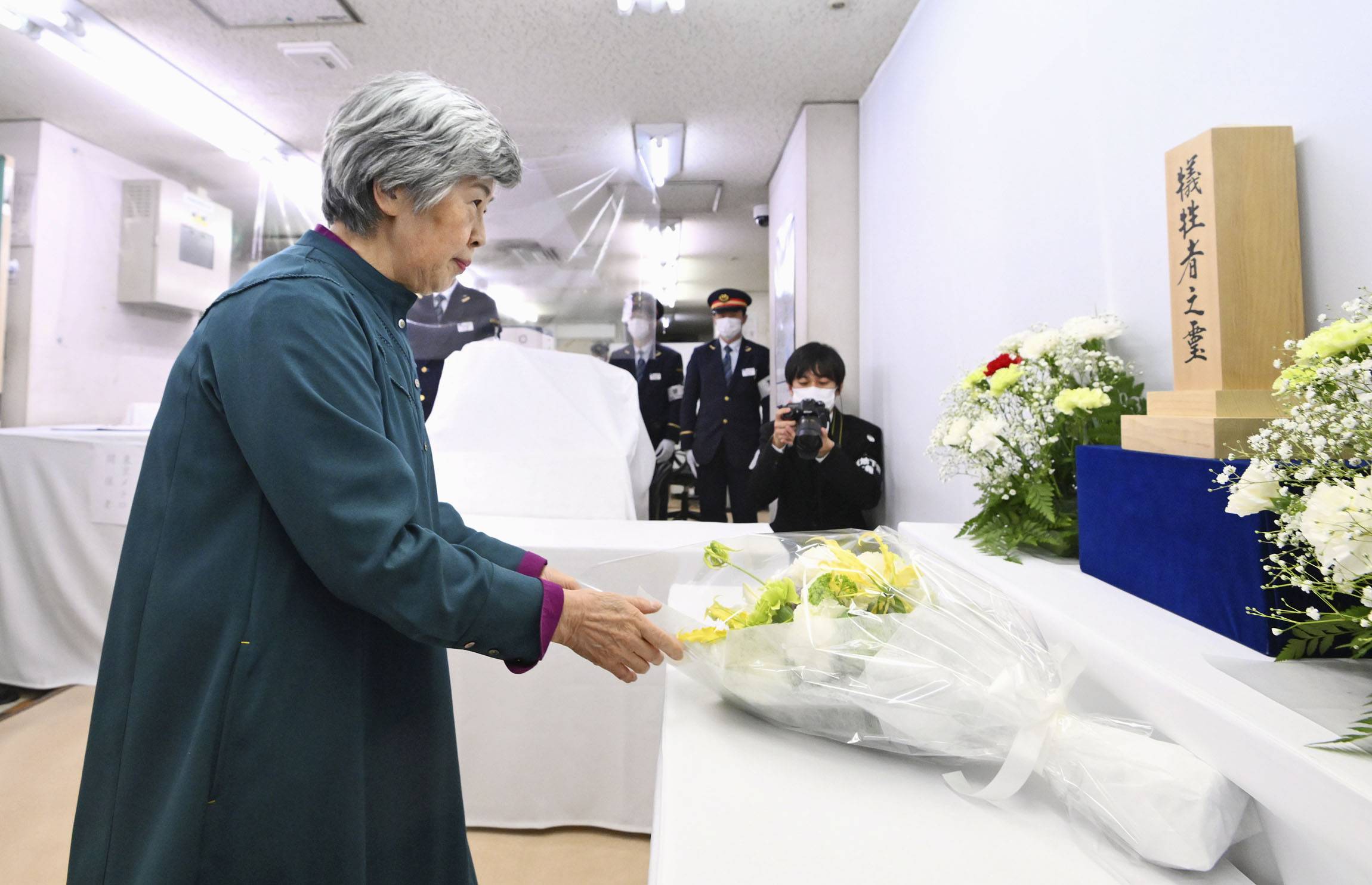 Shizue Takahashi lays flowers at Kasumigaseki Station in Tokyo on Monday, 28 years since the Aum Shinrikyo cult's nerve gas attack on the Tokyo subway system. | POOL / VIA KYODO
