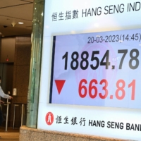 People walk past a sign showing the numbers for the Hang Seng Index in Hong Kong on Monday. | AFP-JIJI