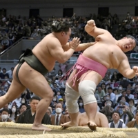 Midorifuji (left) pushes Ura during their bout at the Spring Grand Sumo Tournament in Osaka on Monday. | KYODO