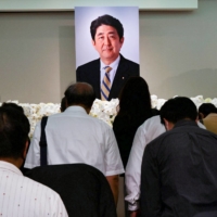 Taiwanese mourners pay their respects to late former Prime Minister Shinzo Abe, who was killed while campaigning for a parliamentary election, in Taipei last July. | REUTERS