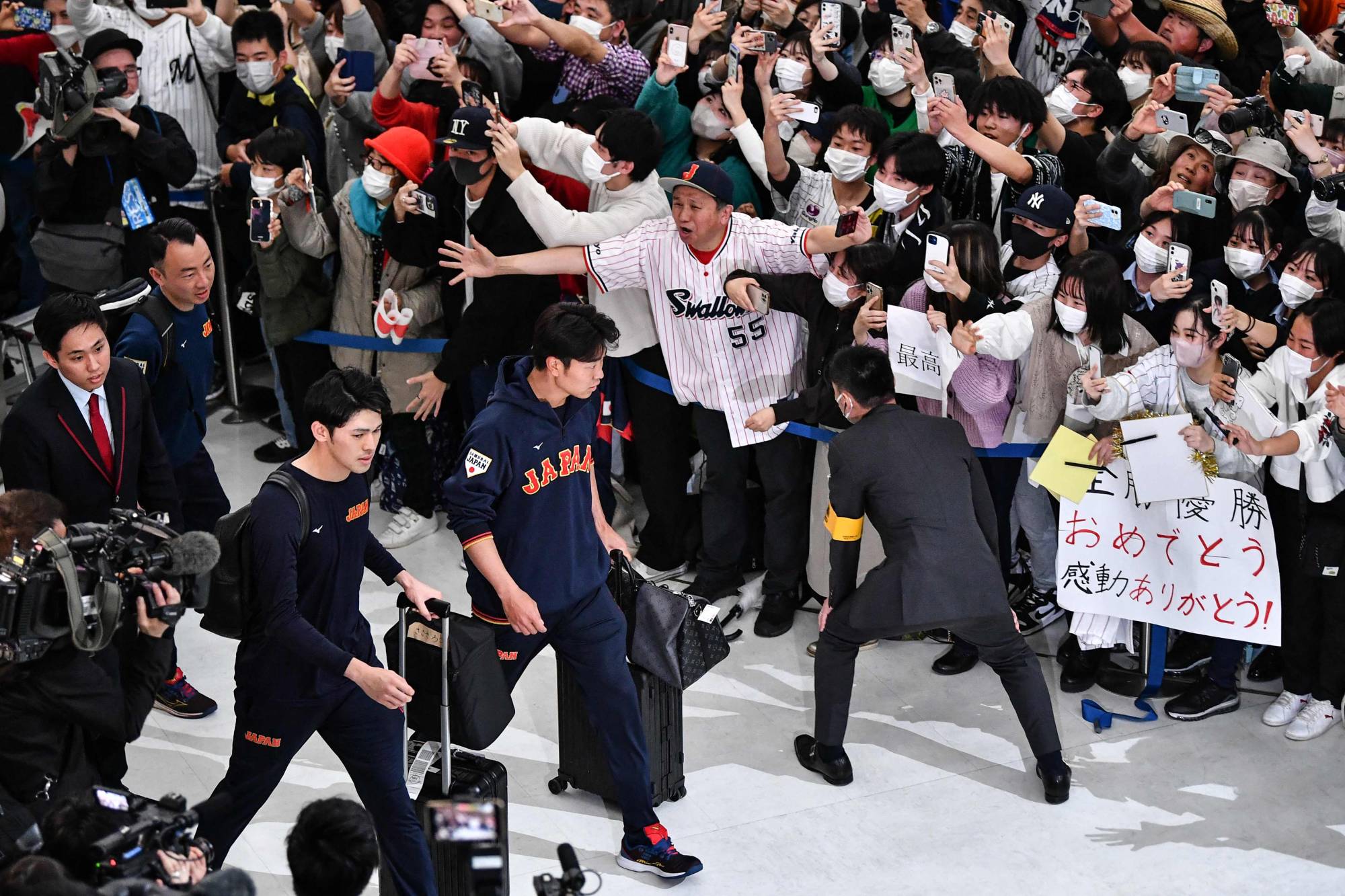 Fans cheer as Samurai Japan players, including pitcher Roki Sasaki, arrive at Narita Airport on Thursday. | AFP-JIJI