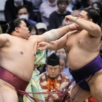 Daieisho (left) attacks Meisei during their Day 13 bout in Osaka on Friday. | KYODO