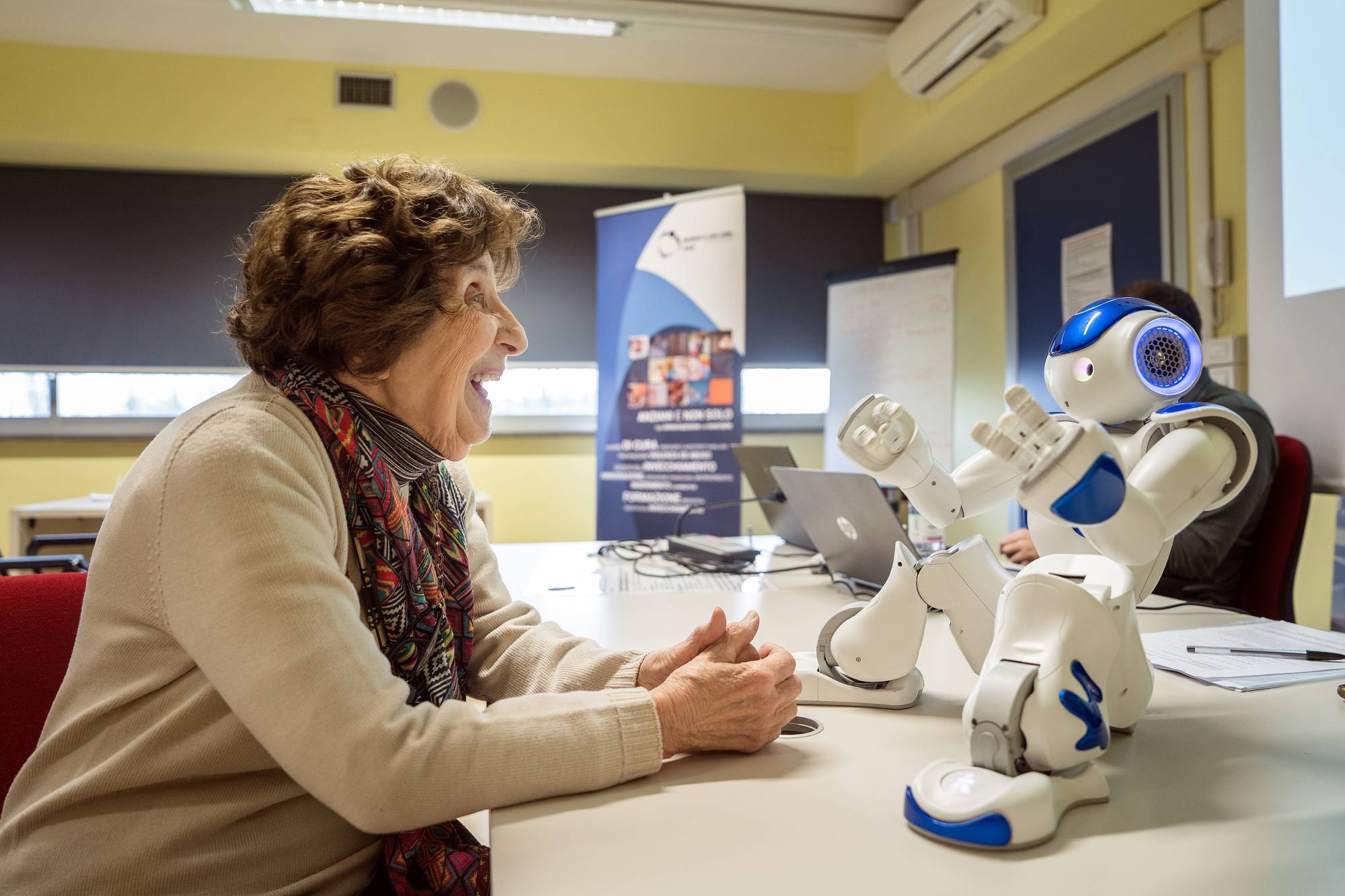 Bona Poli, 85, asks the robot Nao to tell her a story during a focus group in Carpi, Italy, on March 6. The Western world’s oldest population is facing a crisis of caregivers. Some are looking for a little helping, plastic, hand.  | ALESSANDRO GRASSANI / THE NEW YORK TIMES
