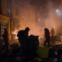 Residents and firefighters try to extinguish a street fire on Thursday during protests in central Paris over Emmanuel Macron’s pension reform plan | BLOOMBERG