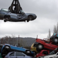 A crane lifts a car to be scrapped at a scrap yard in Gloucester, England, in March 2010. | BLOOMBERG