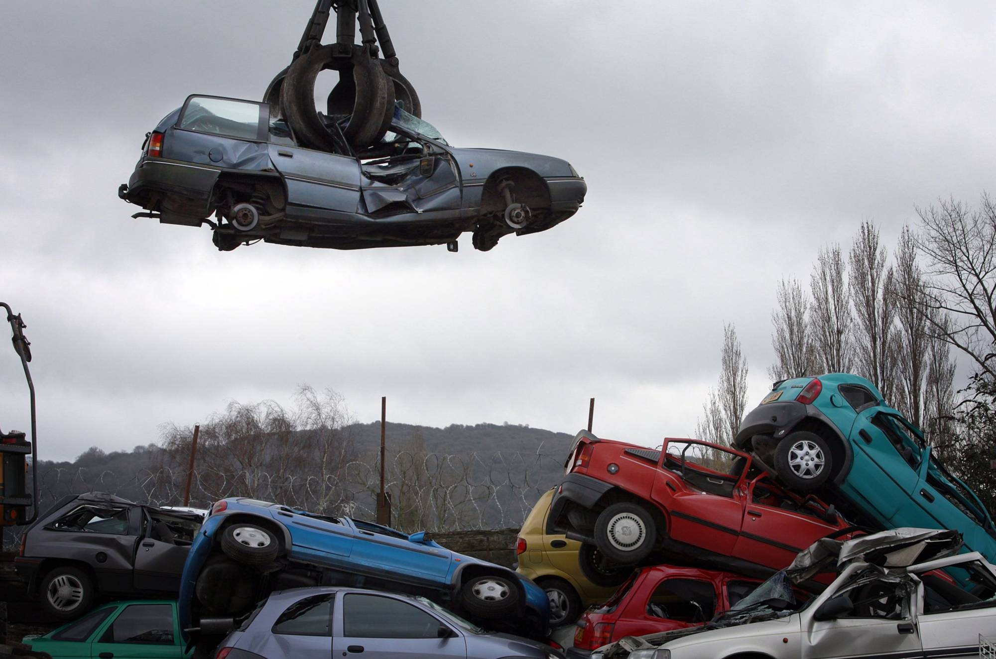 A crane lifts a car to be scrapped at a scrap yard in Gloucester, England, in March 2010. | Bloomberg