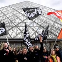 Employees block the entrance of the Musee du Louvre to denounce government\'s controversial pension reform during a demonstration in Paris Monday. 

  | AFP-JIJI
