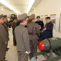 Kim inspects a nuclear weapons project at an undisclosed location in the country, in this image released Tuesday. In the background, a poster appears to show how the green warheads can be mounted on a variety of missiles. | KCNA / KNS / VIA AFP-JIJI 