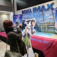 A visitor takes a photo of a poster from the Japanese animation film \'Suzume\' at a movie theater in Beijing on Saturday. | KYODO