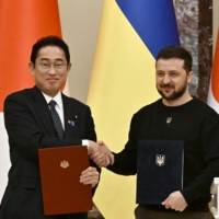 Ukrainian President Volodymyr Zelensky and Prime Minister Fumio Kishida shake hands before their joint press conference, after signing bilateral documents and their meeting in Kyiv on March 21 amid the Russian invasion of Ukraine. | AFP-JIJI