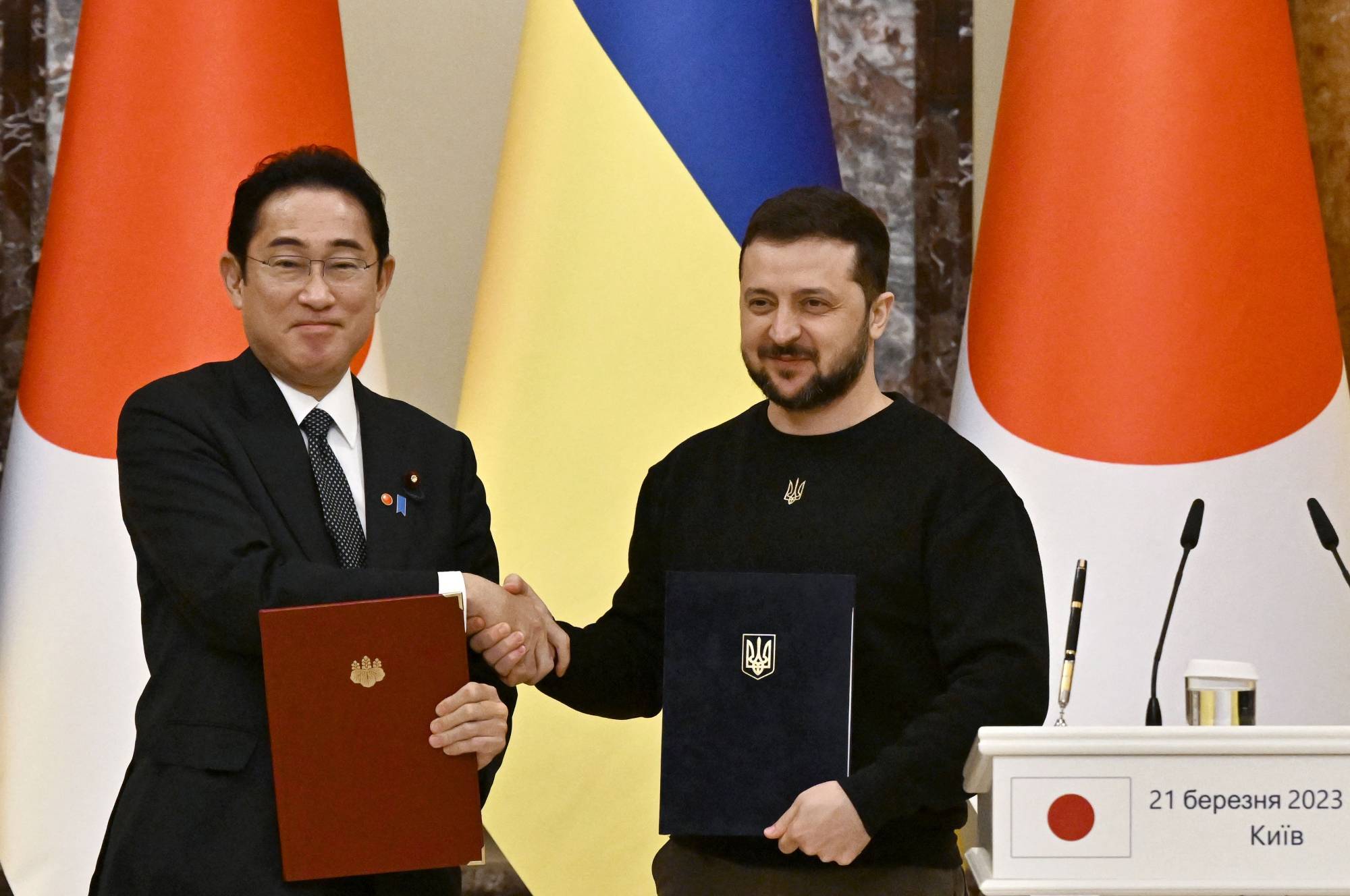 Ukrainian President Volodymyr Zelensky and Prime Minister Fumio Kishida shake hands before their joint press conference, after signing bilateral documents and their meeting in Kyiv on March 21 amid the Russian invasion of Ukraine. | AFP-JIJI