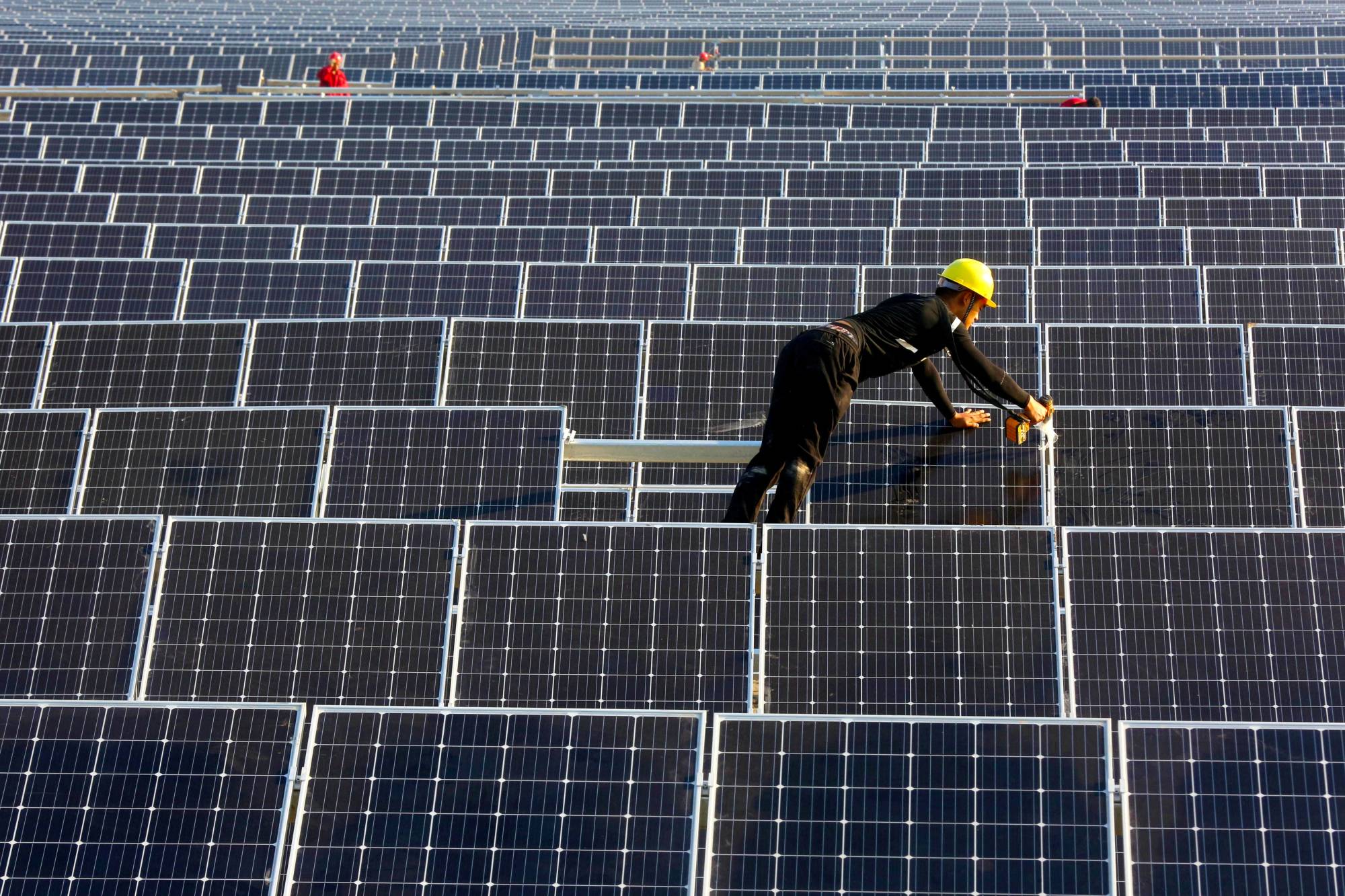 A man works on solar panels at a plant in Huaiyin, China, in 2018.  | REUTERS