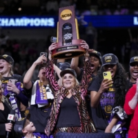 LSU head coach Kim Mulkey lifts the trophy after the team\'s victory over Iowa in the national championship game in Dallas on Sunday. | USA TODAY / VIA REUTERS