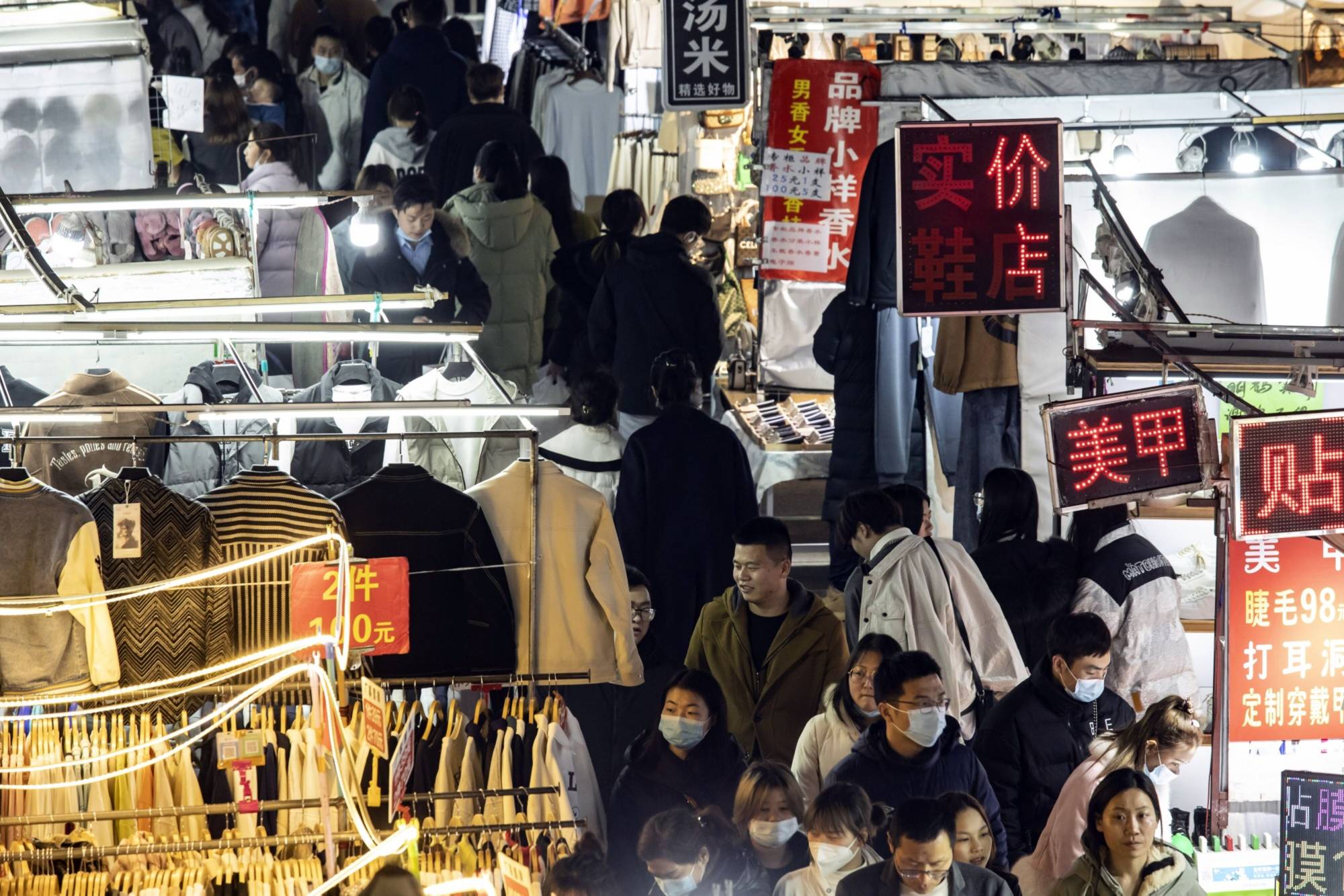 Shoppers pass stalls at a night market in Wuhan, China, on Feb. 6.  | BLOOMBERG