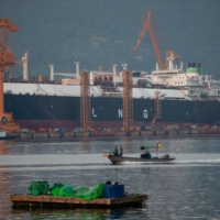 A fishing boat sails past liquefied natural gas tankers under construction at the Daewoo Shipbuilding & Marine Engineering shipyard in Geoje, South Korea, in June 2020. South Korea has broken ground as the first country in Asia to seek to hand out fines for false environmental claims in advertising. | BLOOMBERG