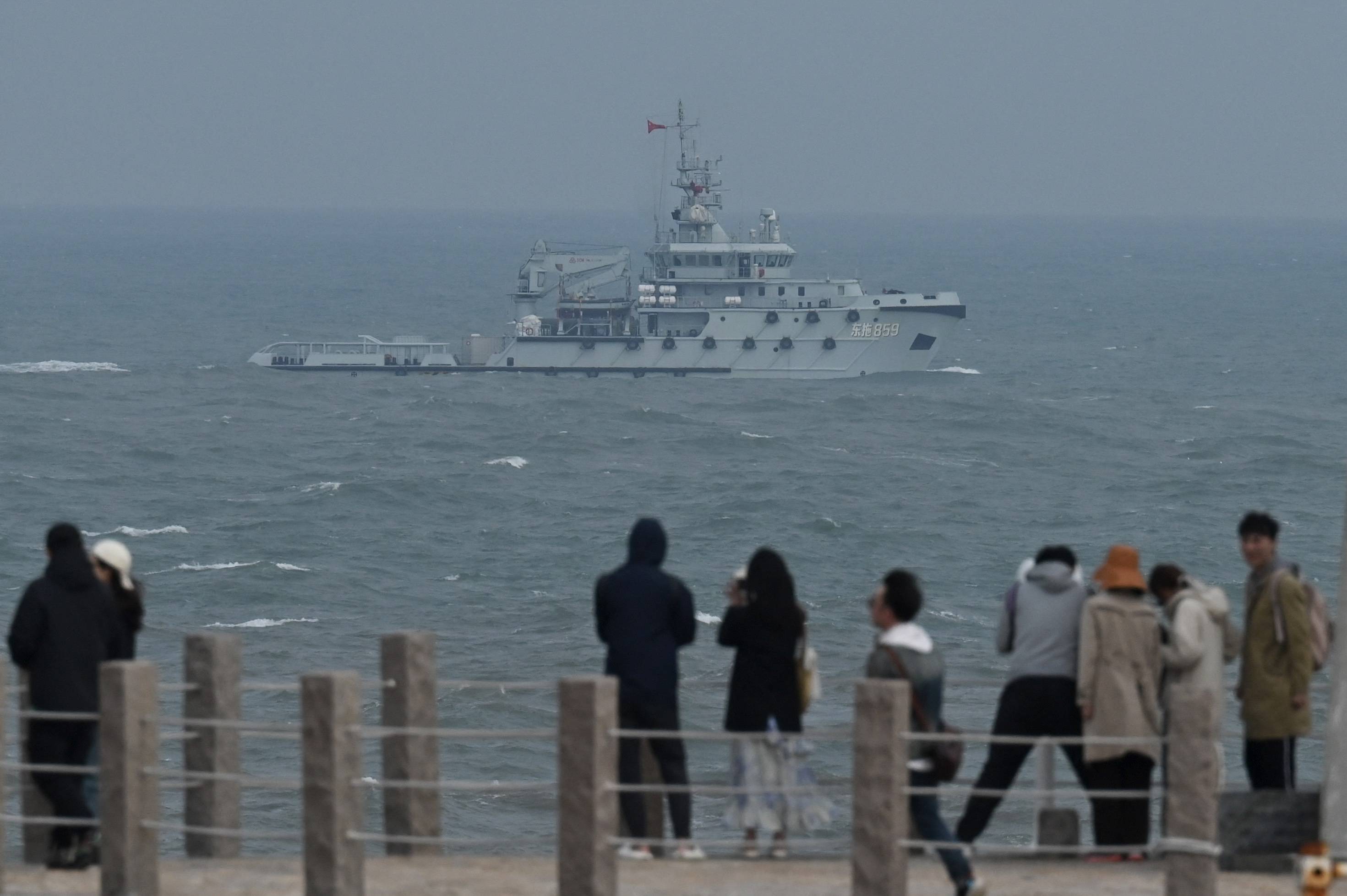A Chinese People's Liberation Army Navy tugboat sails in the Taiwan Strait, past tourists on Pingtan Island, the closest point to Taiwan, in China's southeast Fujian province on Friday. | AFP-JIJI