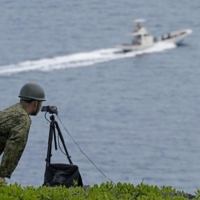 A Self-Defense Force member searches for missing people on Miyako Island in Okinawa Prefecture on Tuesday after a Ground Self-Defense Force helicopter went missing over waters near the island last week. | KYODO