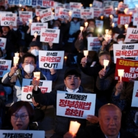 South Korean people chant slogans during a candlelight vigil against a government plan to resolve a dispute over compensating people forced to work under Japan\'s 1910-1945 occupation of Korea, in Seoul on March 6.  | REUTERS