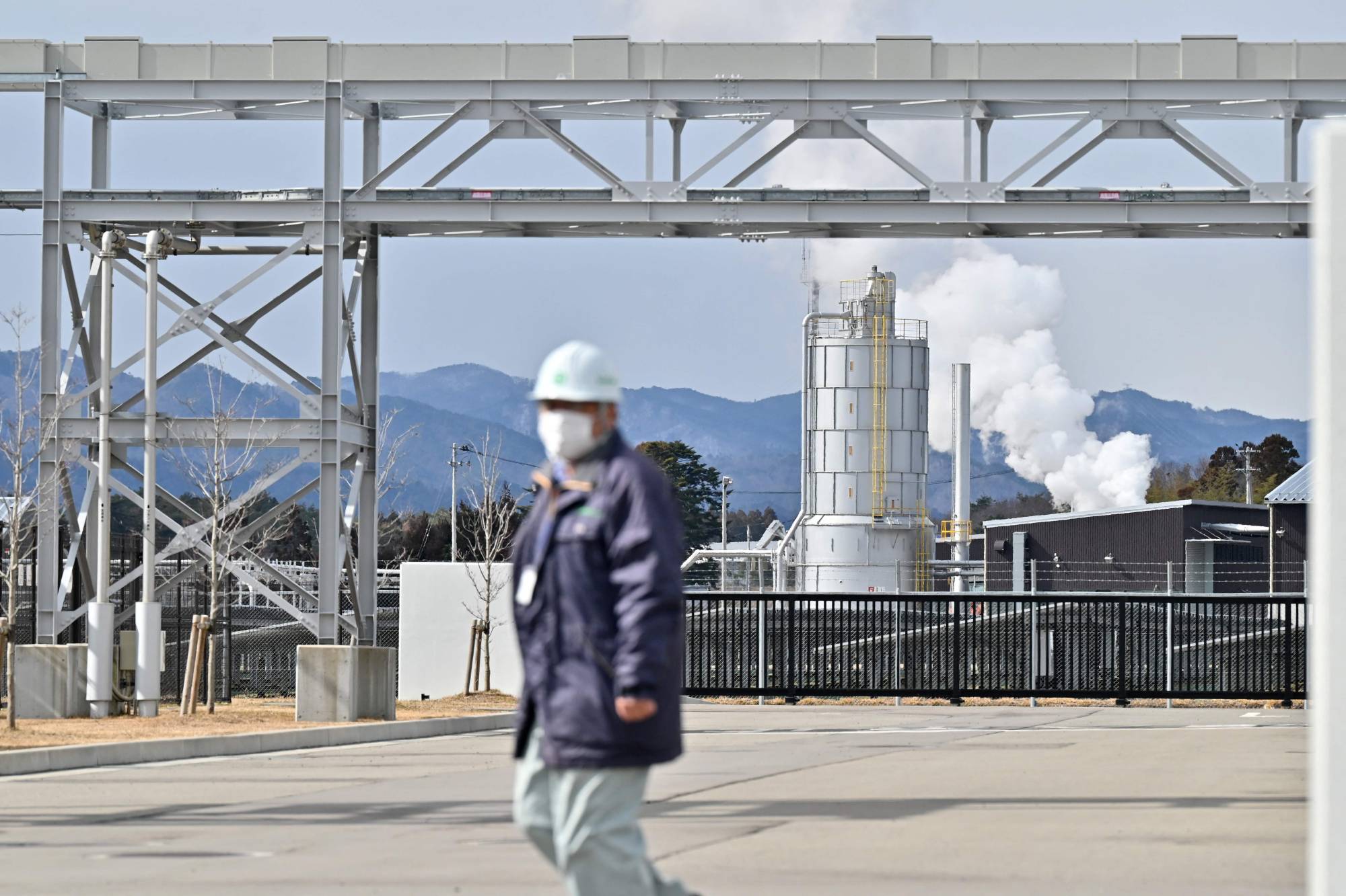 A worker at the Fukushima Hydrogen Energy Research Field, one of the largest test facilities in the world producing hydrogen from renewable energy, during a government-sponsored tour of the area in Namie, Fukushima Prefecture, on Feb. 15. | AFP-JIJI