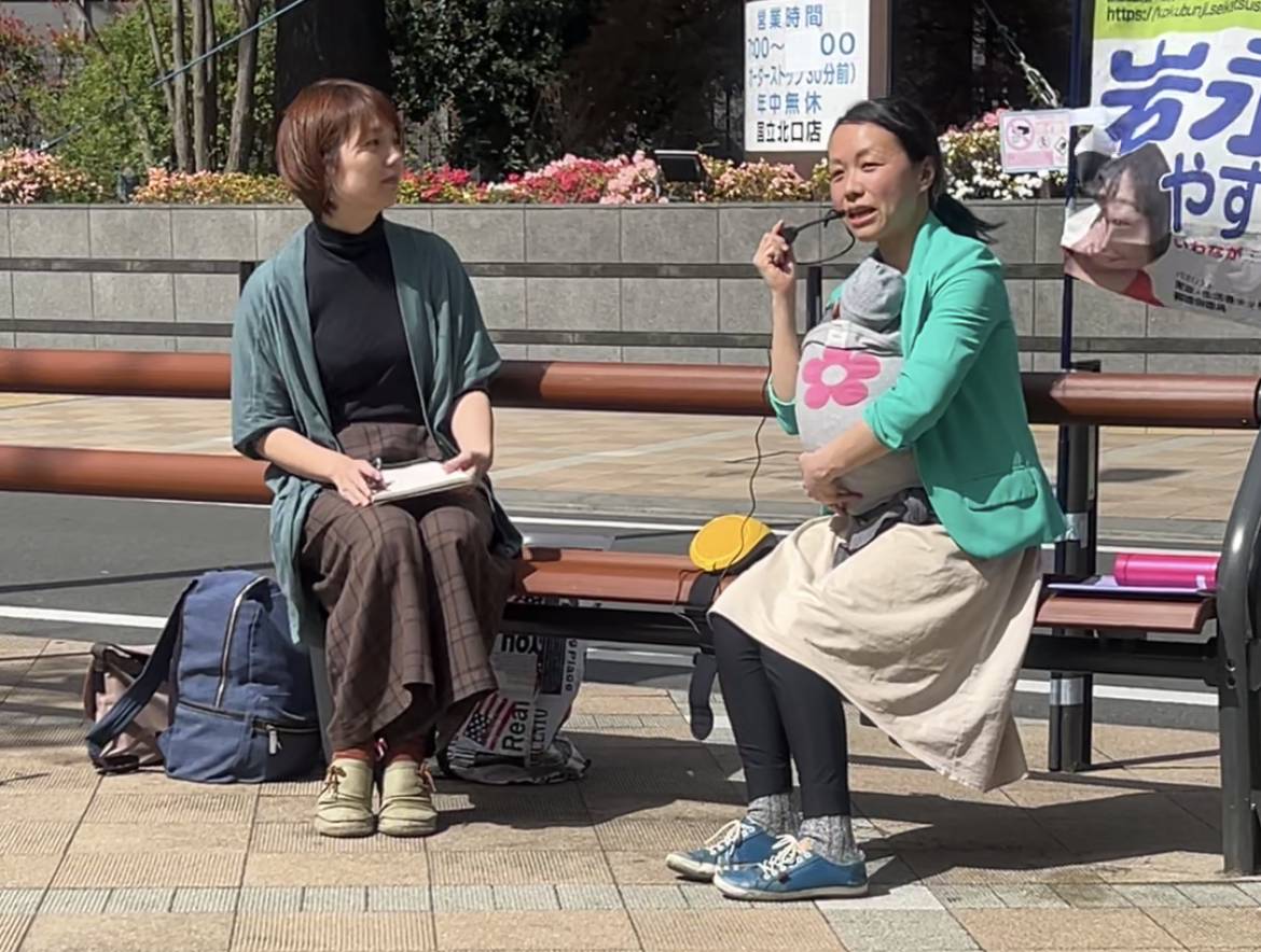 Mari Matsuoka (right) holds a sit-down campaign event, holding her newborn baby, outside JR Kunitachi Station on April 13. | TOMOKO OTAKE