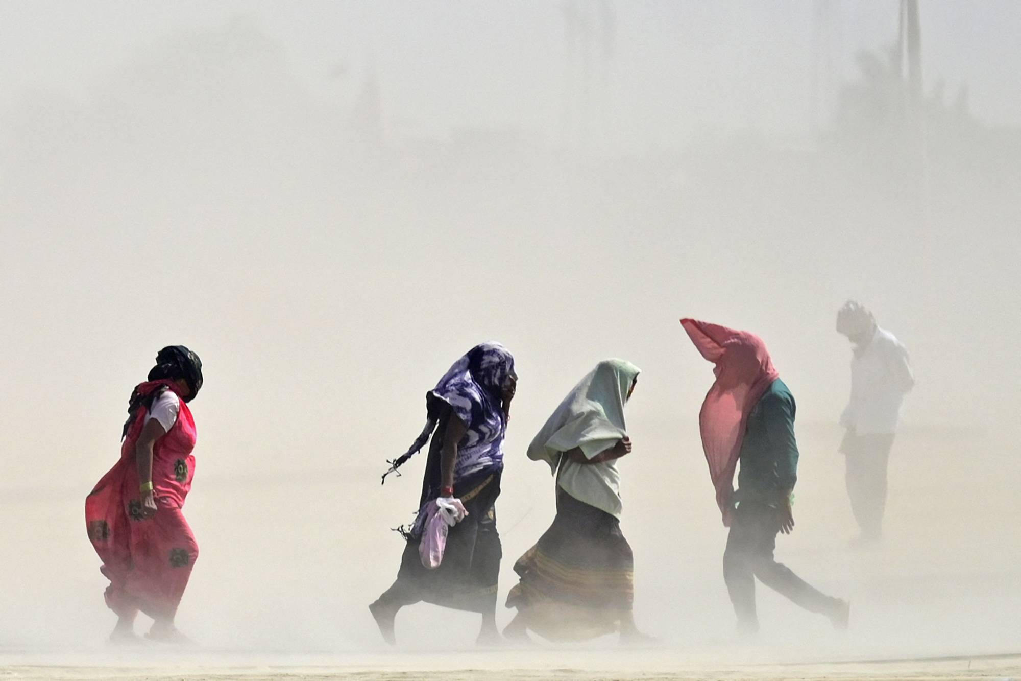 People walk through a dust storm in Prayagraj, India, on Tuesday. | AFP-JIJI