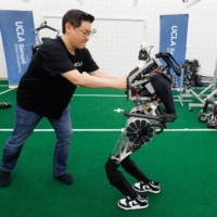 UCLA professor Dennis Hong attempts to impede to movement of ARTEMIS, a humanoid robot developed at UCLA.  | REUTERS