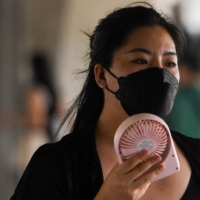 A woman uses a hand fan as temperatures soared in Bangkok on Saturday. | REUTERS