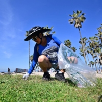 A volunteer cleans up trash at Venice Beach in Los Angeles on Saturday for Earth Day. | AFP-JIJI